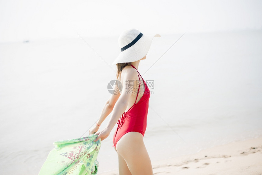 穿红色泳衣的漂亮女人在沙滩上放松夏天的概念图片