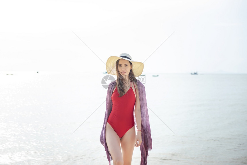 穿红色泳衣的美女正在海上行走夏天概念图片