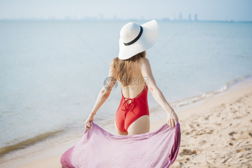 穿红色泳衣的美女正在海滩上散步图片
