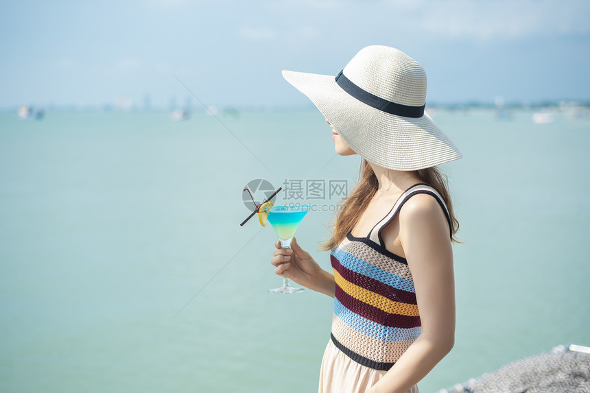 美丽的女人正在海滩喝冰水夏天在海滩喝水夏天的概念图片