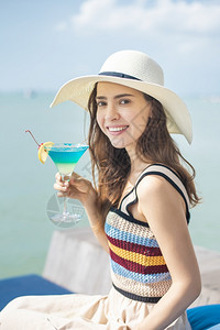 美丽的女人正在海滩喝冰水夏天在海滩喝水夏天的概念图片