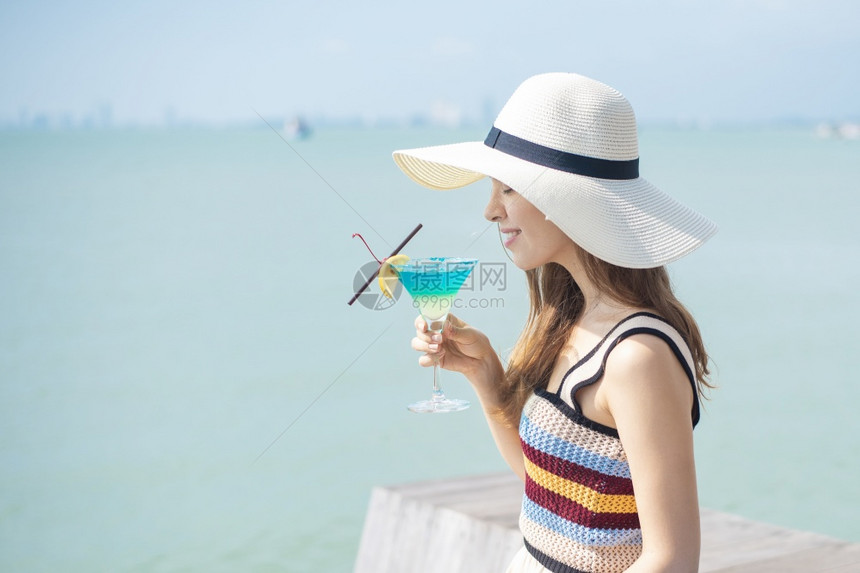 美丽的女人正在海滩喝冰水夏天在海滩喝水夏天的概念图片