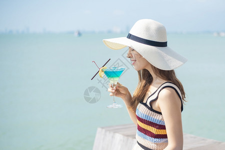 美丽的女人正在海滩喝冰水夏天在海滩喝水夏天的概念图片