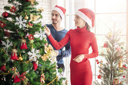 快乐的情侣在家一起装饰圣诞树图片