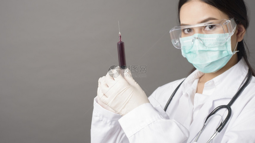 戴外科面罩的医生拿着皮下注射器的女医生图片
