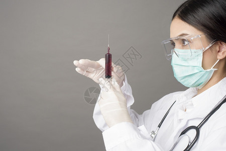 戴外科面罩的医生拿着皮下注射器的女医生图片