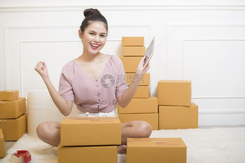 一名妇女正在准备装有纸板箱的产品供运输图片