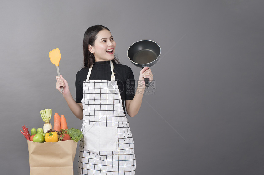 快乐的女子正在准备健康的食物做饭图片