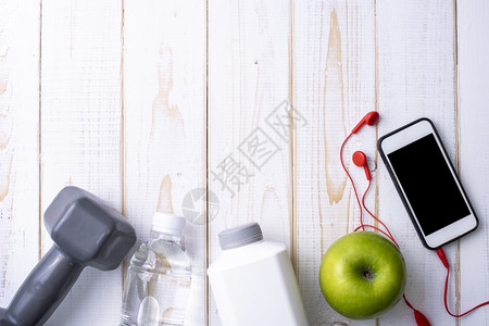 白色木背景的健身设备和康食品图片