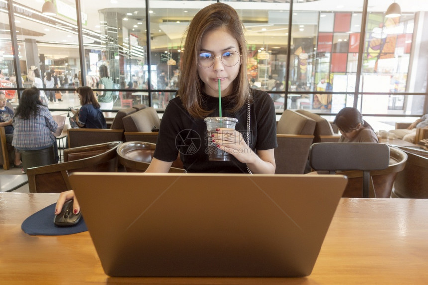 在咖啡店用电脑笔记本工作的美女图片