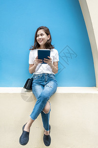 美丽的大学生在蓝墙背景下微笑图片