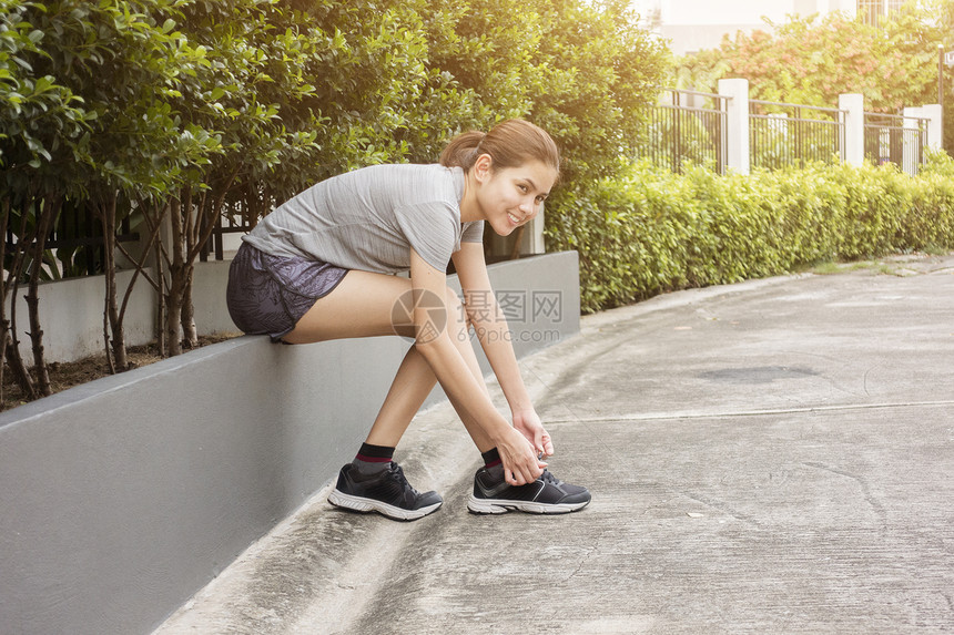 美丽的女人正系着她鞋子图片