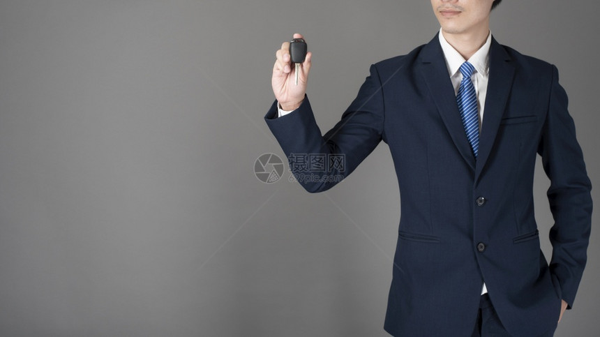生意人拿着车钥匙工作室的灰色背景图片