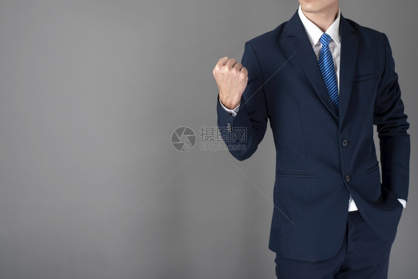 穿着蓝西装的生意人在灰色背景中很成功图片