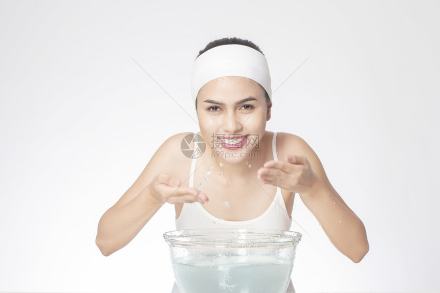 美丽的女人正用白色背景洗脸图片