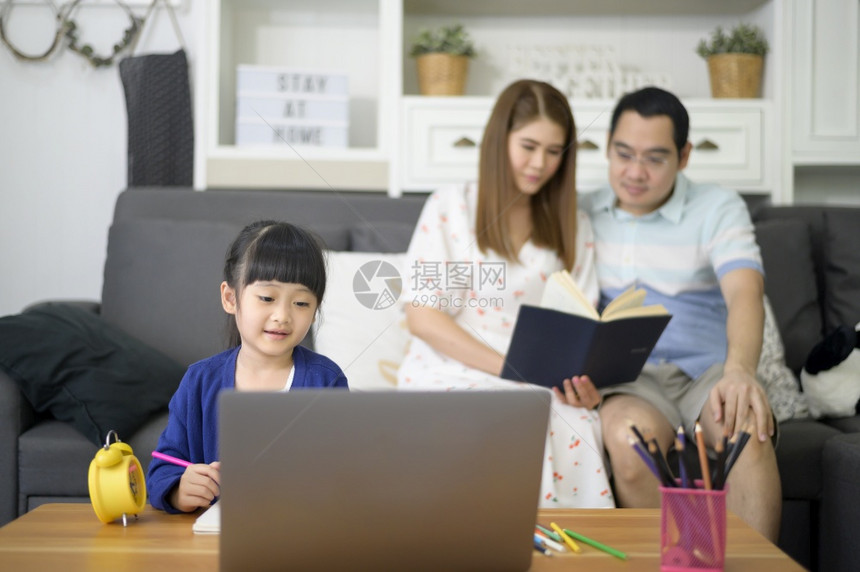 亚洲快乐的女儿正在使用笔记本电脑通过互联网在线学习而父母却坐在家中沙发上图片