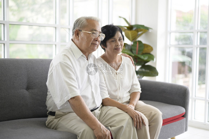 老年亚洲夫妇在沙发上一起坐看电视退休概念老年亚洲夫妇在沙发上一起坐家里看电视退休概念图片