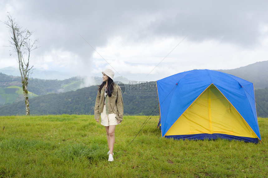 一位快乐的旅游妇女享受和放松在难民营帐篷附近在美丽的绿色山上在雨季热带气候图片