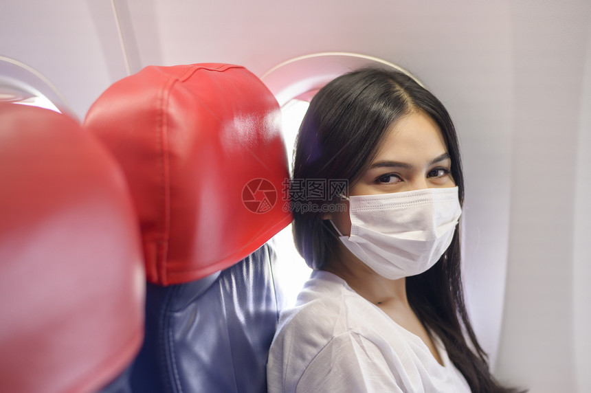一名旅行妇女在飞机上佩戴着口罩图片