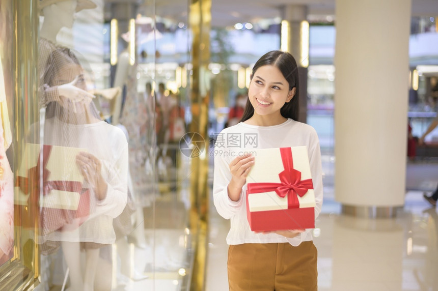 在购物中心感恩节和圣诞概念中持有礼品盒的妇女图片