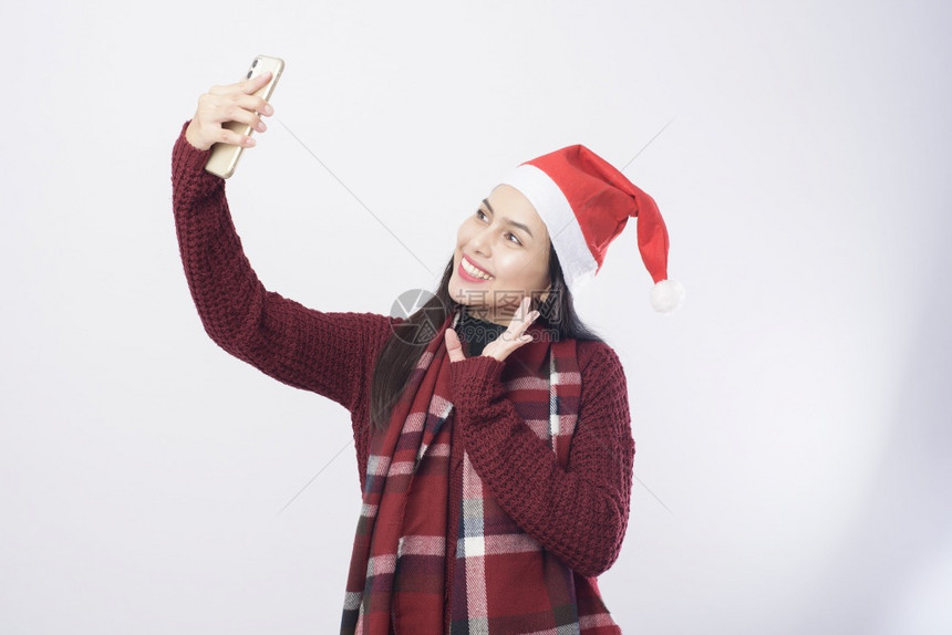 穿着红色圣诞老人帽子的年轻微笑女人在白色背景工作室拍自图片