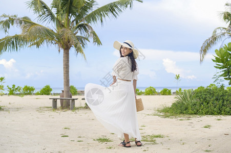 凉鞋白裙子一个穿着白裙子的快乐美丽女人在海滩夏天和节假日享受放松背景