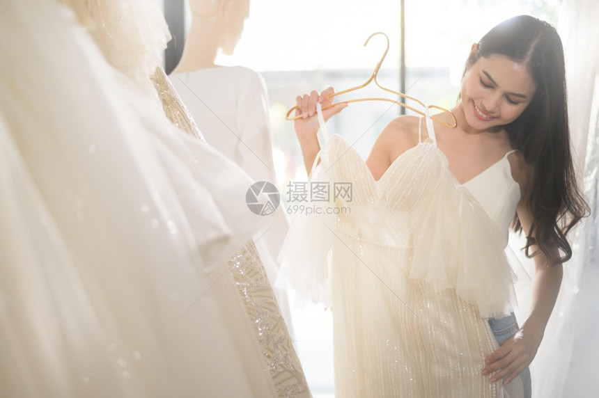 年轻美丽的新娘在婚礼工作室选择结婚装束姻概念图片