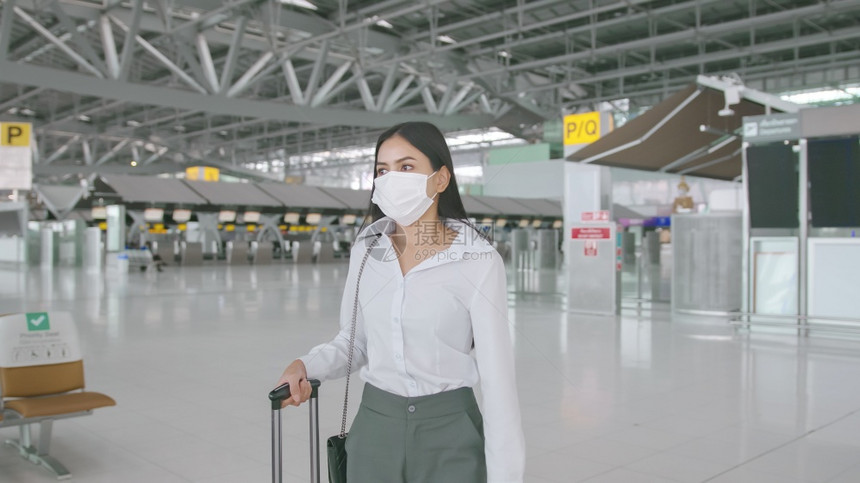 一名商业妇女在国际机场佩戴保护面具在新冠大流行下旅安全社会不和协议新正常旅行概念图片