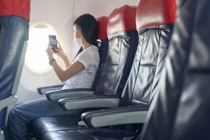 一名佩戴口罩的女子在飞机上使用智能手表图片