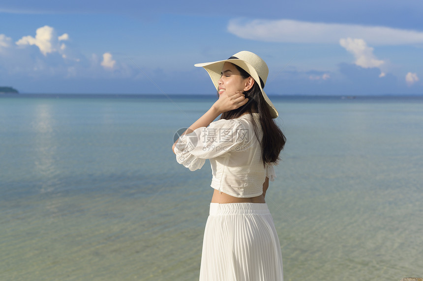 一个穿着白裙子的快乐美丽女人在海滩夏天和节假日享受放松图片