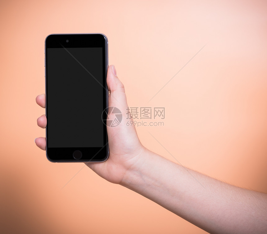 持有移动智能手机的女加上橙色背景的空白屏幕图片