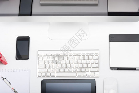 办公室监测台白桌上的计算机视网膜显示鼠键盘移动电话平板和空白屏幕图片