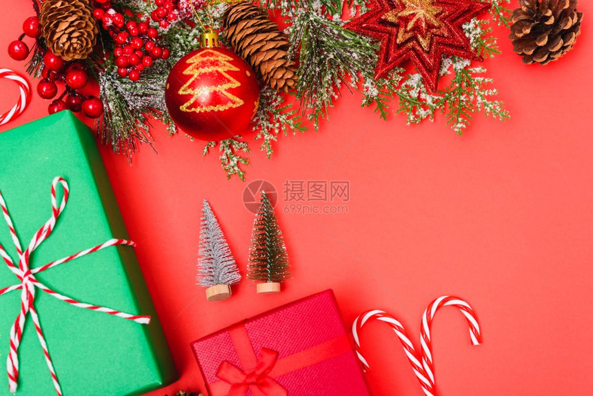 圣诞绿色礼物箱和装饰品红背景的fir树枝圣诞快乐概念带有文本复制空间图片