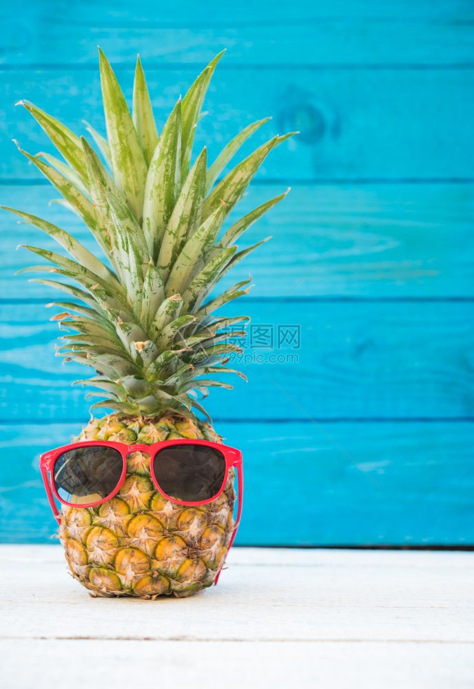 度假菠萝有蓝木背景的太阳镜热带假日概念图片