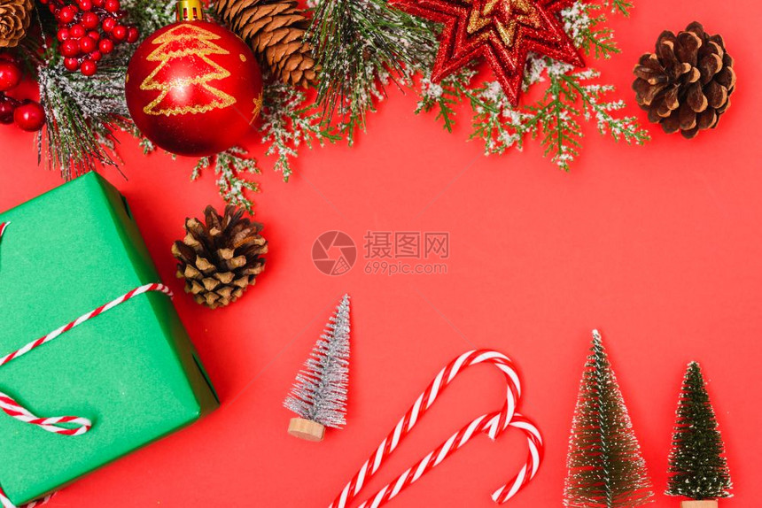 圣诞绿色礼物箱和装饰品红背景的fir树枝圣诞快乐概念带有文本复制空间图片