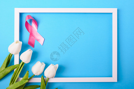乳癌月概念平铺顶楼粉色丝带图利普花蓝色背景照片框和文本复制空间图片