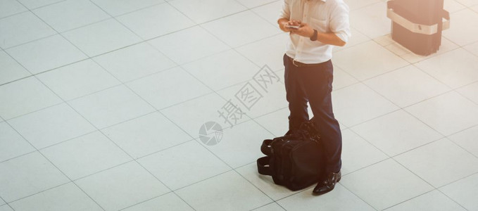 男子拿着行李在机场用智能手机图片