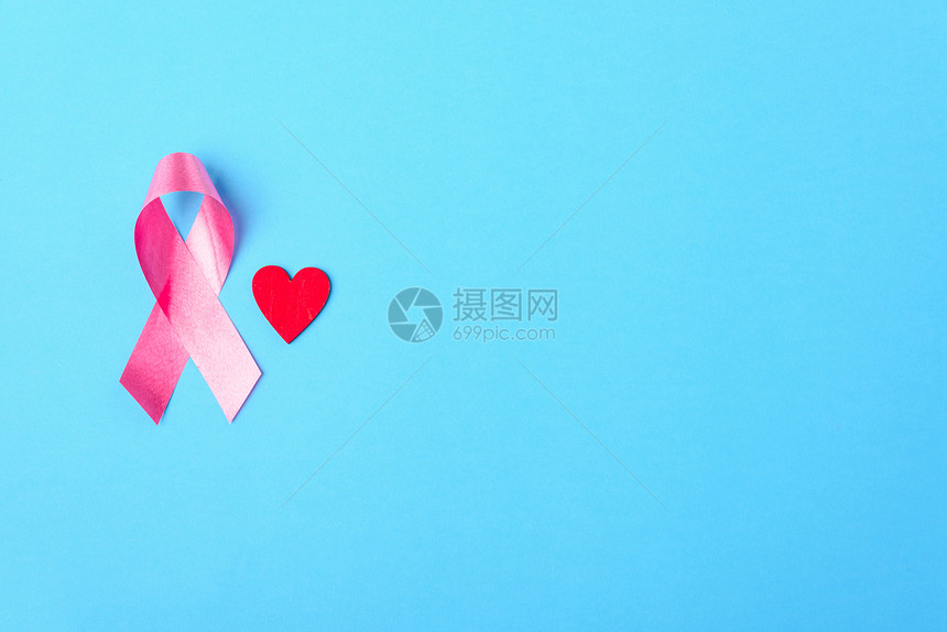乳癌月概念平铺顶楼粉红丝带和心放在蓝色背景上并附文本的复制空间图片