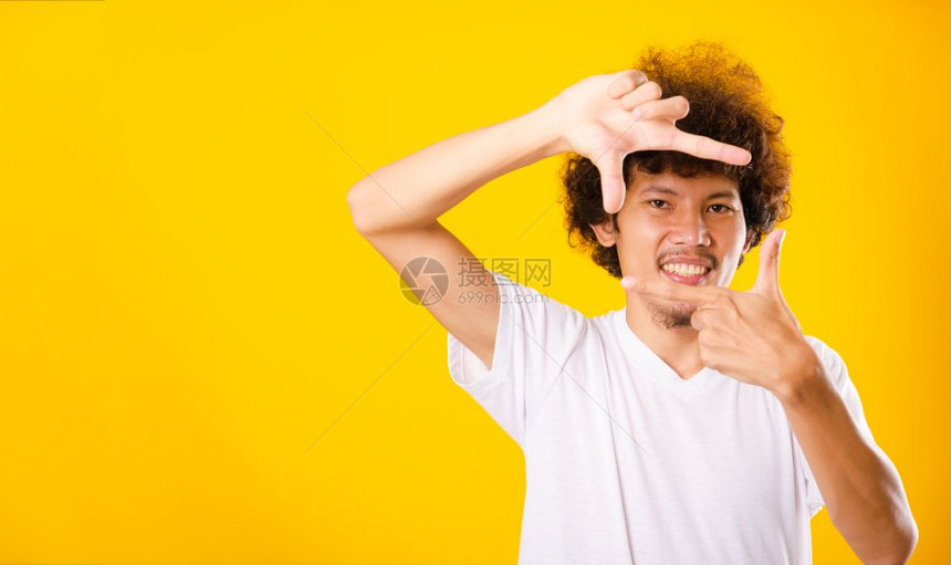亚洲长着卷发的帅男子他笑着用手和指做架子图片