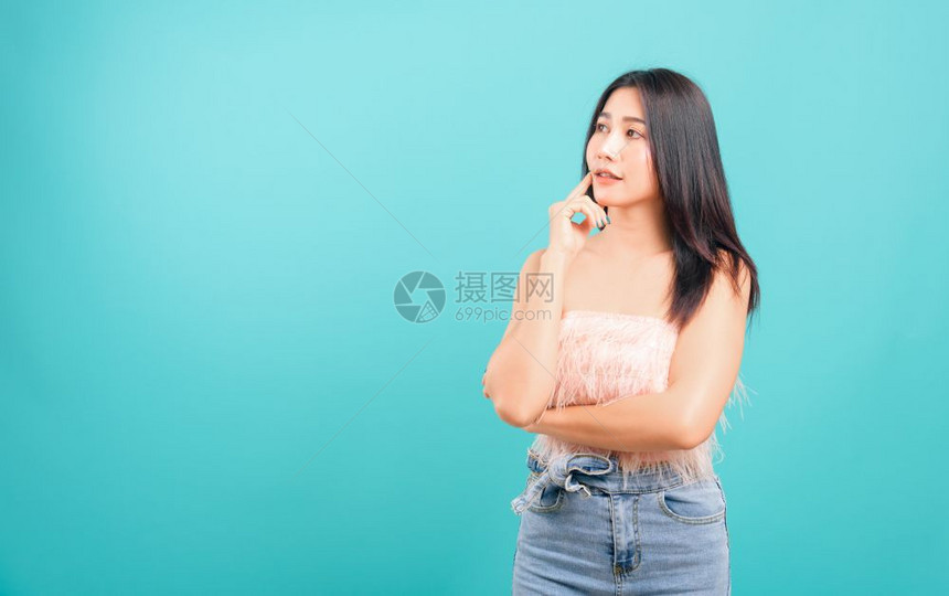 肖像般的亚洲美丽女微笑着她站立的思考看着蓝背景复制文本空间图片