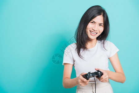 身穿T恤运动衫的亚洲美丽年轻女子穿着T恤运动机手握棍棒或游戏板蓝背景有复制空间背景图片