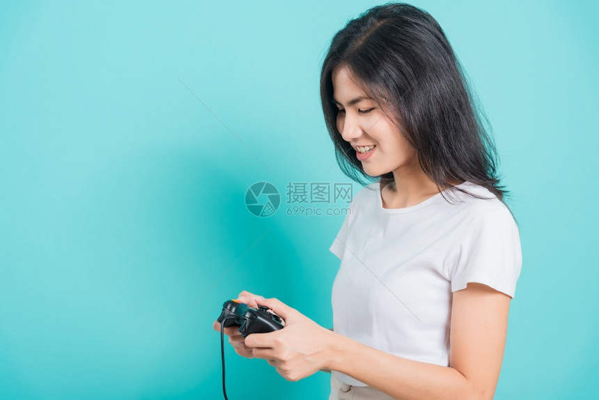 身穿T恤运动衫的亚洲美丽年轻女子穿着T恤运动机手握棍棒或游戏板蓝背景有复制空间图片