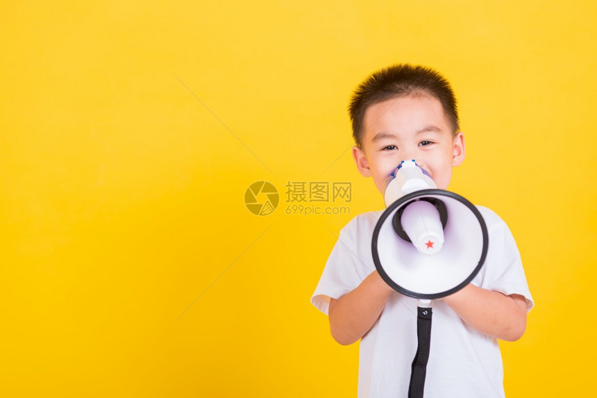 亚裔泰国快乐肖像可爱的小快乐男孩拿着喊叫或尖在扩音器上图片
