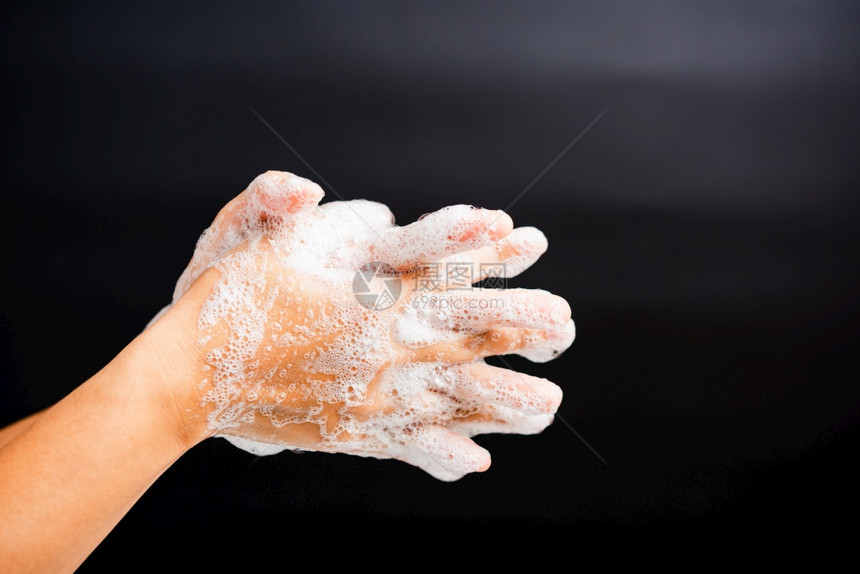 亚洲青年妇女用肥皂洗手时有泡沫卫生预防COVID19或冠状保护概念以黑色背景隔离图片