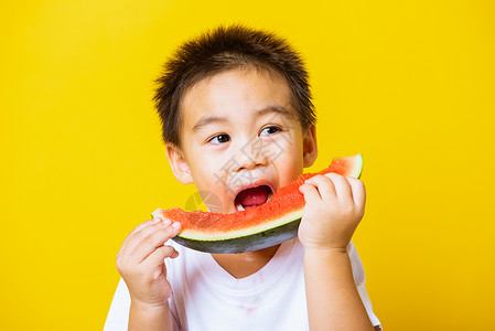 快乐的亚洲儿童或孩子可爱的小男孩笑玩着切开西瓜新鲜食物拍片室摄孤立在黄色背景上健康食物和夏季概念背景图片