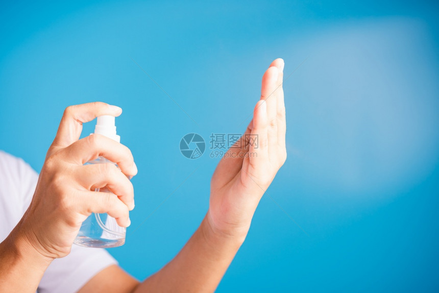 使用喷泵洒器净化剂酒精洗手清洁卫生预防COVID19或蓝底隔离的冠状保护概念的亚洲青年妇女图片