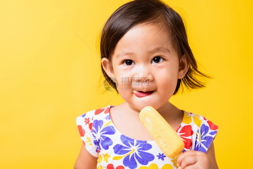 快乐的亚洲小婴儿或孩可爱的女快乐肖像笑有吸引力的小女孩笑穿着鸡样衬衫并吃甜木冰淇淋摄影棚拍着黄色背景夏季概念图片