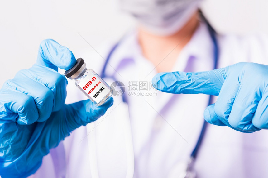 身穿制服的亚洲女医生或护士身戴面罩的手套在实验室中用瓶状科罗纳疫苗和子指着上面贴有COVID19CoRONAVIRUSVACCI图片