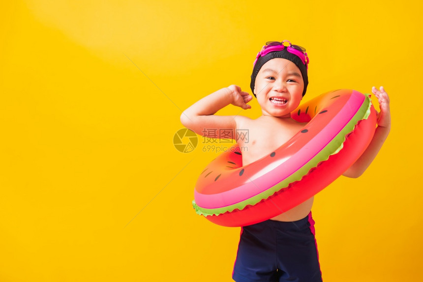 暑假概念肖莱特亚洲快乐可爱的小男孩穿着护目镜和泳衣抓着西瓜的充气环基德在暑假玩得开心工作室拍摄孤立的黄色背景图片