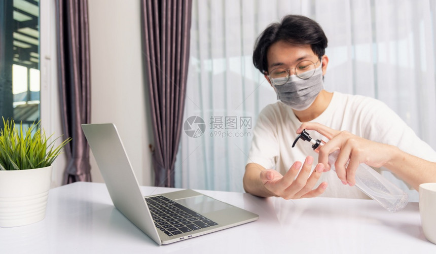 亚洲商人年轻英俊帅男眼镜在家办公室工作他隔离疾病冠状毒或COVID19戴防护面具在前笔记本电脑上用防污胶洗手图片